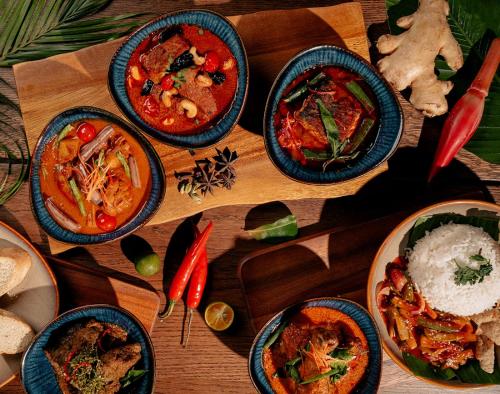 una mesa de madera cubierta con cuencos de diferentes tipos de comida en Tune Hotel KLIA Aeropolis (Airport Hotel) en Sepang