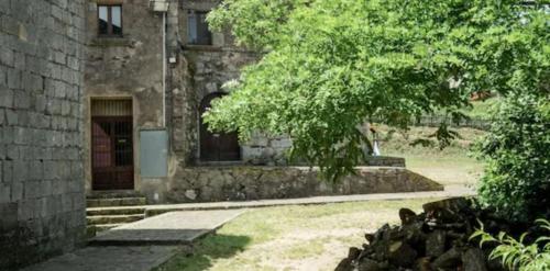 un vecchio edificio in pietra con una porta e un albero di Rectoria Santuari del Coll a Girona