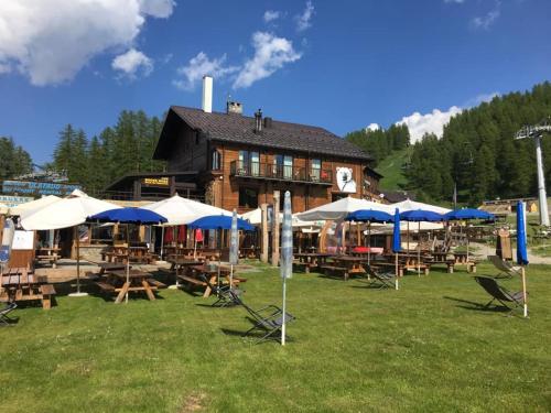 eine Gruppe von Tischen und Sonnenschirmen vor einem Gebäude in der Unterkunft Orso Bianco Hotel & Chalet in Sauze dʼOulx