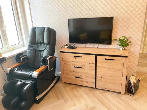 una silla de cuero negro sentada frente a un televisor en Apartment Nicol, en Karlovy Vary