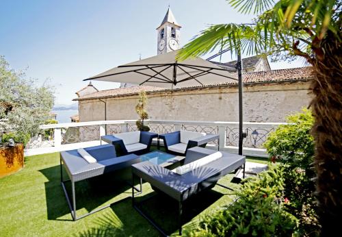 eine Terrasse mit einem Tisch, Stühlen und einem Sonnenschirm in der Unterkunft Hotel Al Campanile - Luxury Suites & Apartments in Baveno