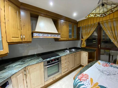 a kitchen with wooden cabinets and a stove top oven at Apartamento El Rincón de Pilar in El Astillero