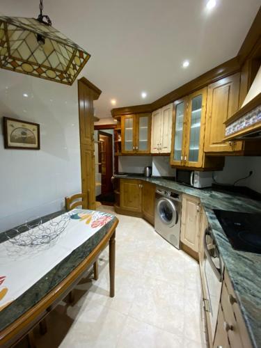 a kitchen with wooden cabinets and a washer and dryer at Apartamento El Rincón de Pilar in El Astillero