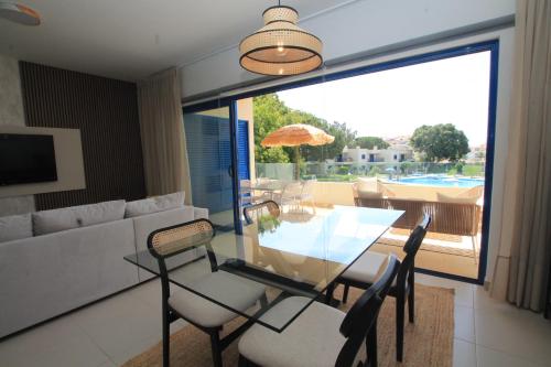 een woonkamer met een tafel en stoelen en een bank bij Aldeamento Bemposta - Pool & Garden Bemposta in Alvor