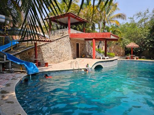 une piscine avec toboggan et des personnes dans l'eau dans l'établissement Rancho Agua Salada, à Alpuyeca