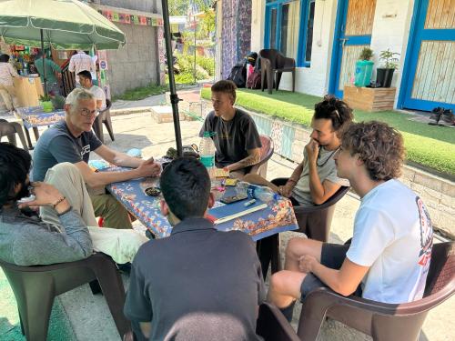 een groep mensen die rond een tafel schaken bij Tiny Spot Hostel in Manāli