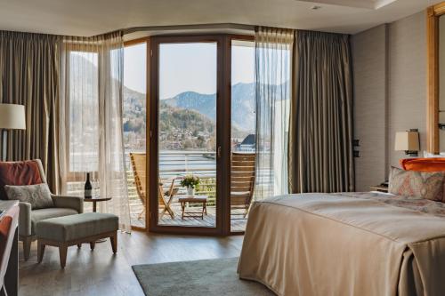 - une chambre avec un lit et un balcon avec vue dans l'établissement Althoff Seehotel Überfahrt, à Rottach-Egern