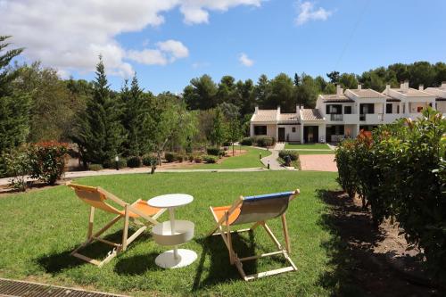 two chairs and a table in front of a house at Apartamento com terraços privativos em resort de luxo in Alvor