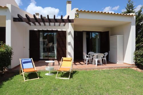 a patio with chairs and a table in a yard at Apartamento com terraços privativos em resort de luxo in Alvor