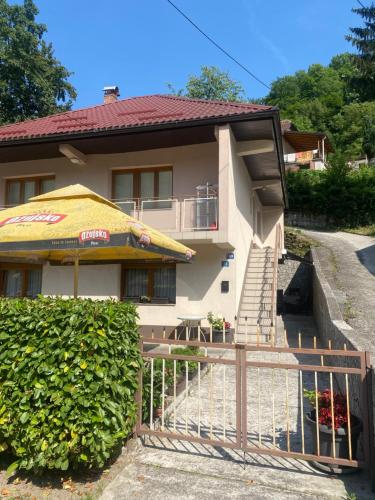 ein Haus mit einem gelben Regenschirm und einem Zaun in der Unterkunft Hana1 in Konjic