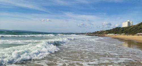 uma vista para a praia a partir do oceano com ondas em Lovely 2 bedroom Flat at Palm Court in Bournemouth,5 minutes away from beach, whole flat is yours for the time you stayed em Bournemouth