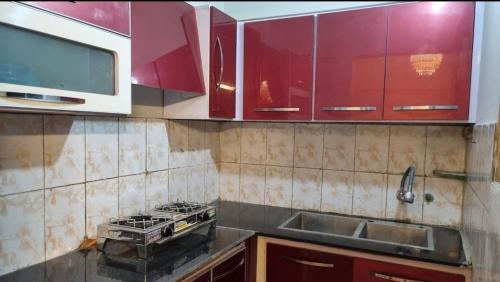 a kitchen with red cabinets and a stove and sink at Furnished One Bedroom appartment with kitchen in Karachi