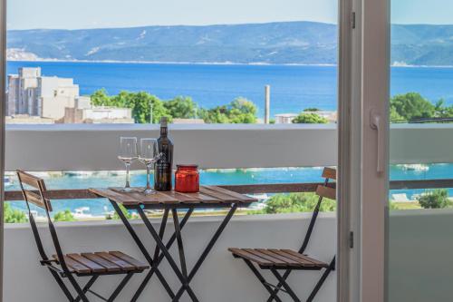 a table with two chairs and wine glasses on a balcony at Skyline Suite in Omiš