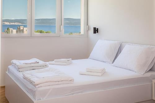 a white bed with towels on it in a room with two windows at Skyline Suite in Omiš