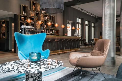 un vestíbulo con sillas azules y una mesa en Motel One Lübeck, en Lübeck