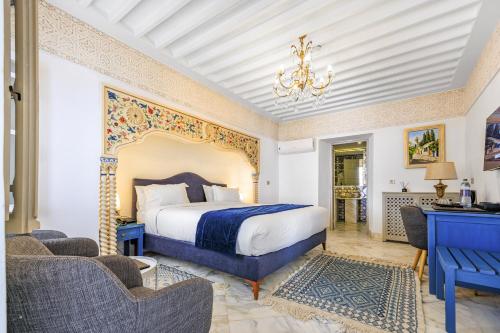 1 Schlafzimmer mit einem großen Bett und 2 Stühlen in der Unterkunft La Menara Hotel & SPA in Sidi Bou Saïd