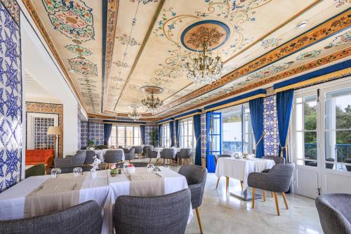 a restaurant with tables and chairs and a ceiling with paintings at La Menara Hotel & SPA in Sidi Bou Saïd