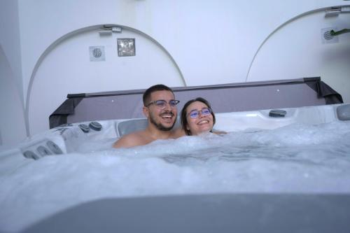 un homme et une femme assis dans une baignoire dans l'établissement Guest House Jacarandá Faro, à Faro