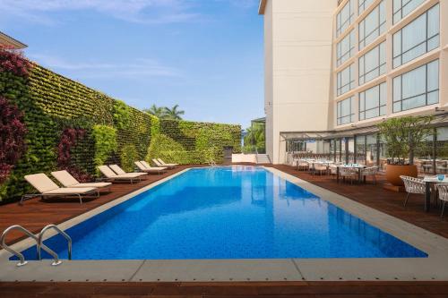 Courtyard by Marriott Goa Colva في كلفا: مسبح مع كراسي جلوس بجانب مبنى