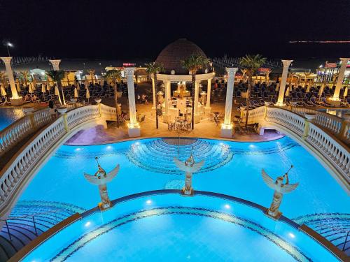 a pool at night with people jumping in the water at Imperial Palace Hotel in Sunny Beach