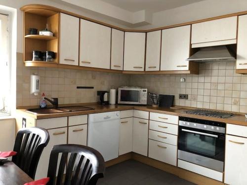 a kitchen with white cabinets and a stove top oven at Ferienhaus Schwanennest in Zell an der Mosel