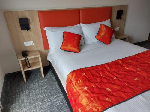 a bedroom with a large bed with red pillows at Hôtel de L'ile in Custines