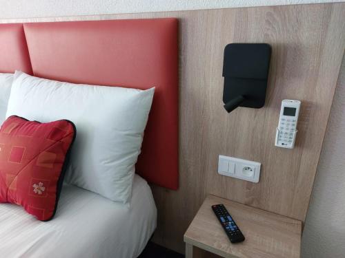 a hotel room with a bed and a phone on a wall at Hôtel de L'ile in Custines