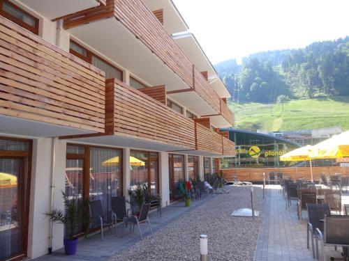 un edificio con sillas, mesas y sombrillas en Hotel Planai by Alpeffect Hotels, en Schladming