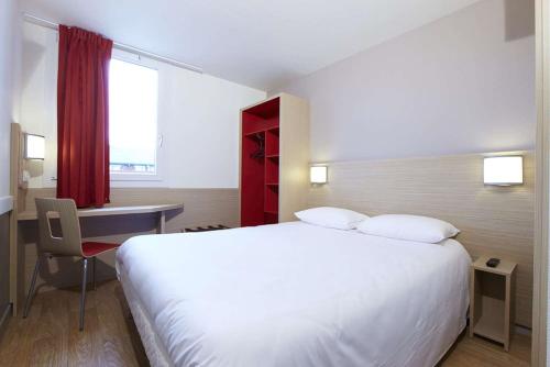 um quarto com uma grande cama branca e uma secretária em B&B HOTEL Saint-Witz Roissy em Saint-Witz