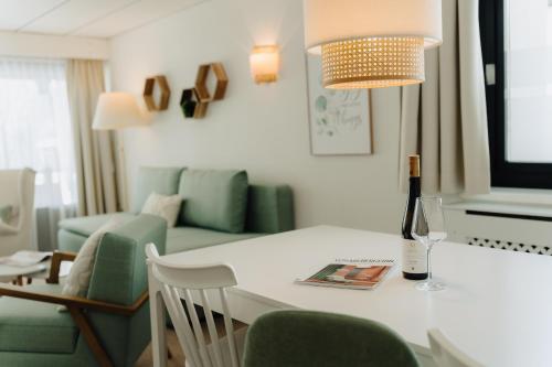 una mesa blanca con una botella de vino y una copa de vino en Apartment Hotel Pfeifer, en Gaschurn