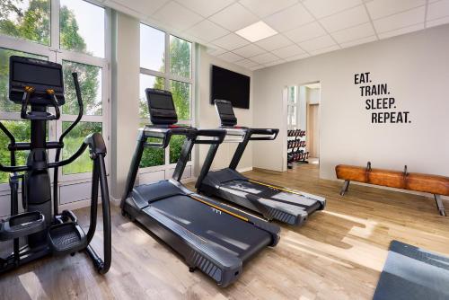 une salle de sport avec trois tapis de course et un tapis de course dans l'établissement Courtyard by Marriott Dortmund, à Dortmund