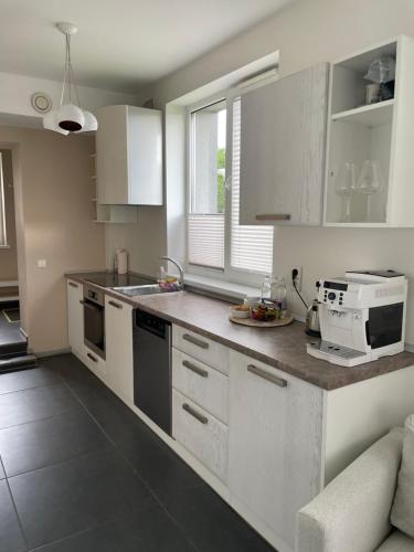 a kitchen with white cabinets and a counter top at JZ apartamentai in Kelmė