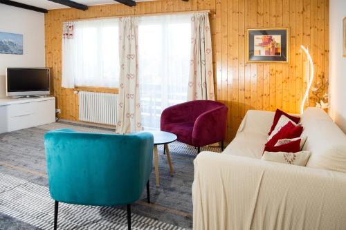 ein Wohnzimmer mit einem Sofa, Stühlen und einem TV in der Unterkunft Ski in Ski out Family accommodation Chesa Katja Lenzerheide in Valbella