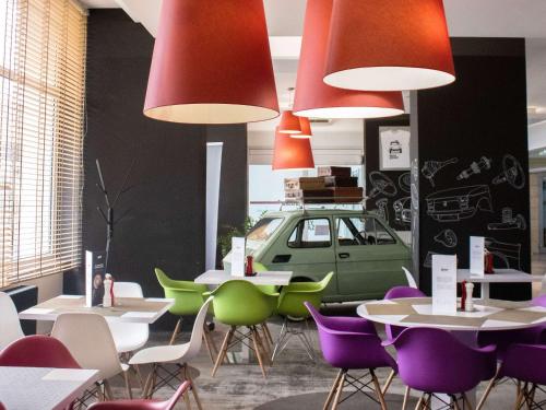 un ristorante con tavoli e sedie con un'auto appesa al muro di ibis Styles Bielsko Biala a Bielsko-Biała