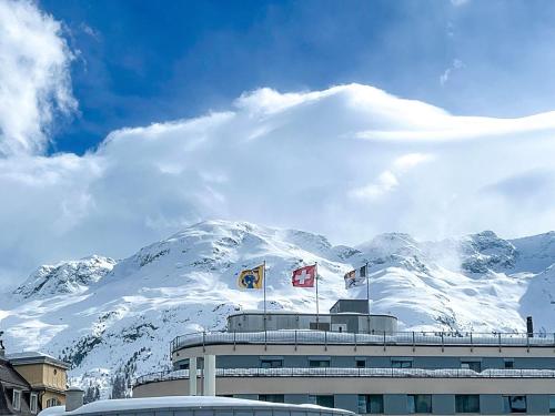 una montaña cubierta de nieve con banderas en la parte superior de un edificio en Sankt Moritz Suite, en St. Moritz