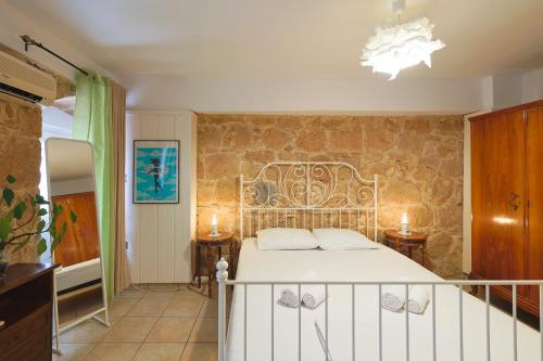 - une chambre avec un lit et un mur en pierre dans l'établissement Stenaki - Apartments in Aegina Town, à Égine