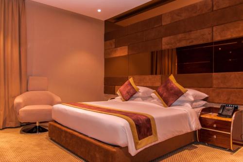 a bedroom with a large bed and a chair at City Park Hotel Apartments in Muscat