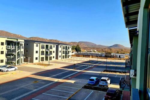 um parque de estacionamento com carros estacionados em frente a um edifício em Cozy 1-Bed Apartment in Gaborone em Gaborone