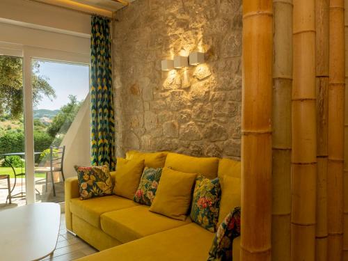 a yellow couch in a living room with a stone wall at Kotroni Villas in Finikounta