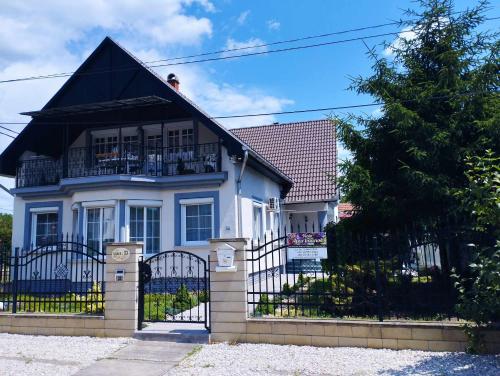 a white house with a black roof and a gate at Viola Apartmanház in Bogács