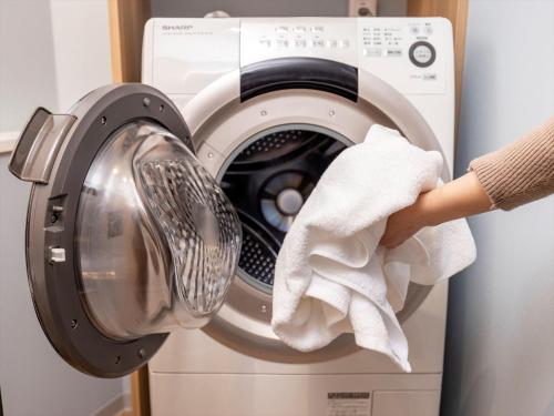 a person holding a towel in front of a washing machine at Tokyu Stay Shimbashi - Ginza area in Tokyo