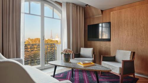 uma sala de estar com uma mesa e cadeiras e uma grande janela em Hotel Lutetia em Paris