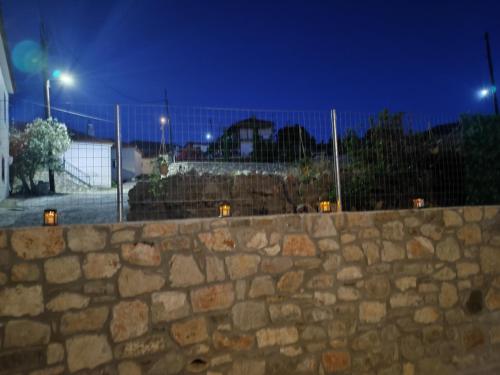 a stone wall in front of a fence at night at Vaki's country house in Pylos