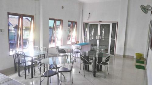 a dining room with tables and chairs and windows at Avicenna Hotel in Palangkaraya