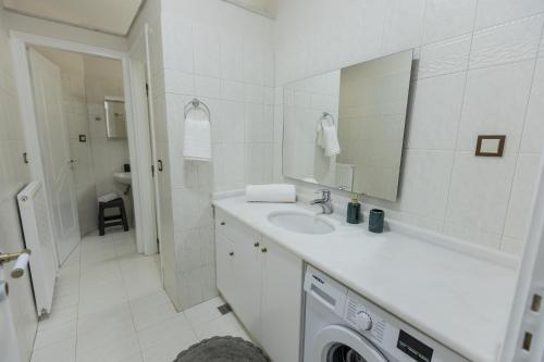 a white bathroom with a sink and a washing machine at ΑμφιΘΕΑ! στη ΝΑΥΠΑΚΤΟ ! in Nafpaktos