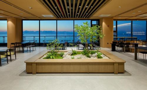 - un hall avec des tables et des chaises et une grande fenêtre dans l'établissement Ramada by Wyndham Gangwon Sokcho, à Sokcho