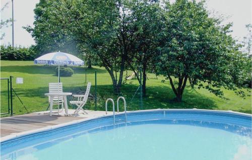 uma piscina com mesa e cadeiras e um guarda-sol em Le Saule em Ucimont