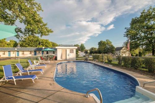 a swimming pool with chairs and a house at Rodeway Inn in Rutland