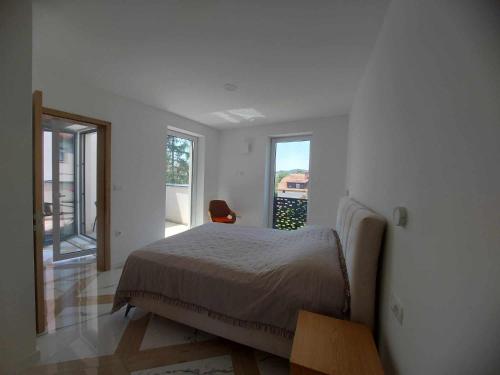 a white bedroom with a bed and a window at PALAR Apartment in Ljubljana