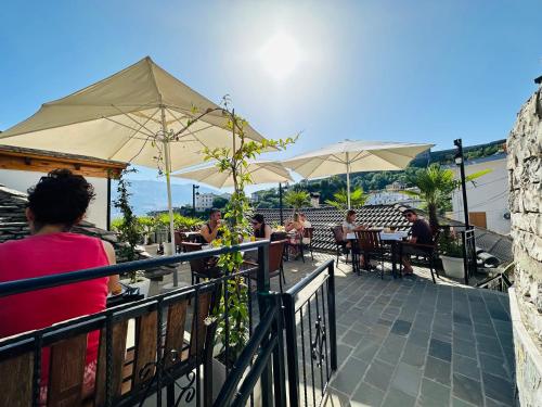 un groupe de personnes assises dans un restaurant avec des parasols dans l'établissement Kore Guest House, à Gjirokastër